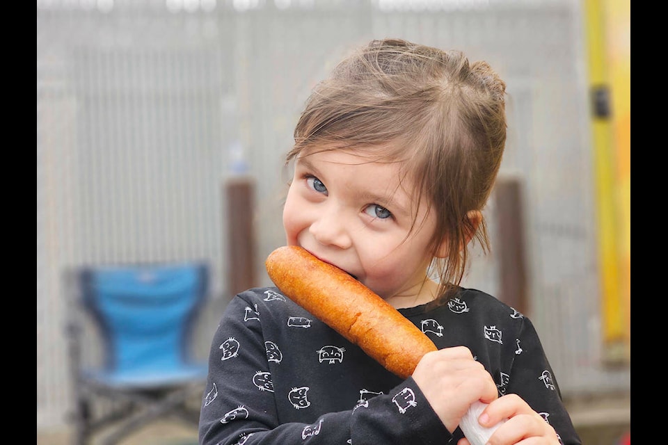 Emersyn, five, from Maple Ridge, devoured a corn dog at the third annual Food Truck Wars event at KPU in Langley on Saturday, April 20. A little later, organizers had to close early because of gusting winds. (Dan Ferguson/Langley Advance Times) 