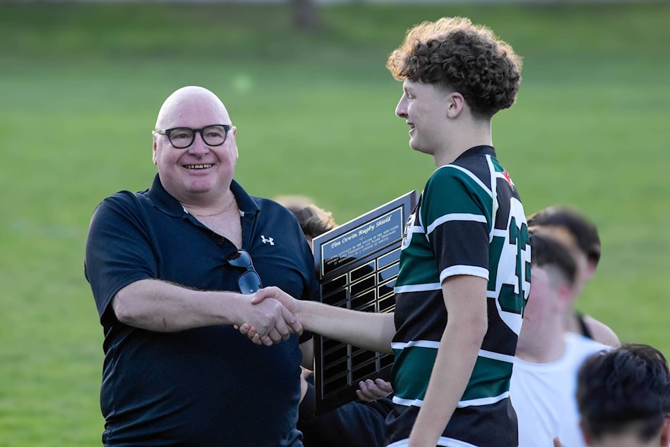 Tim Oswin presents Lord Tweedsmuir captain Connor Brown with the Oswin Rugby Shield April 19. LT won the inaugural contest for the new shield. (Photo submitted: Marcus Tam) 