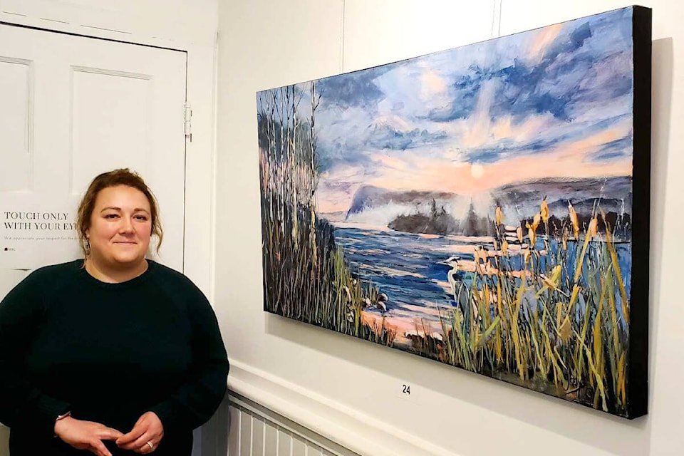 Station House Gallery executive director Davana Stafford stands next to Sunrise; Scout Island by Gladys Wheatley, one of the pieces of artwork up for blind bid in the gallery’s An Artful Night Out event taking place Friday, May 10 at Thompson Rivers University café. (Monica Lamb-Yorski photo - Williams Lake Tribune) 