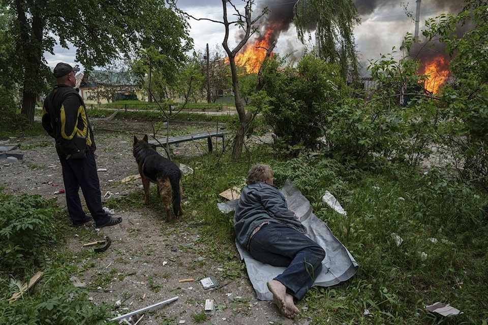 A man lies on the ground as he watches his burning house destroyed by a Russian airstrike in Vovchansk, Ukraine, on Saturday, May 11, 2024. (AP Photo/Evgeniy Maloletka) 