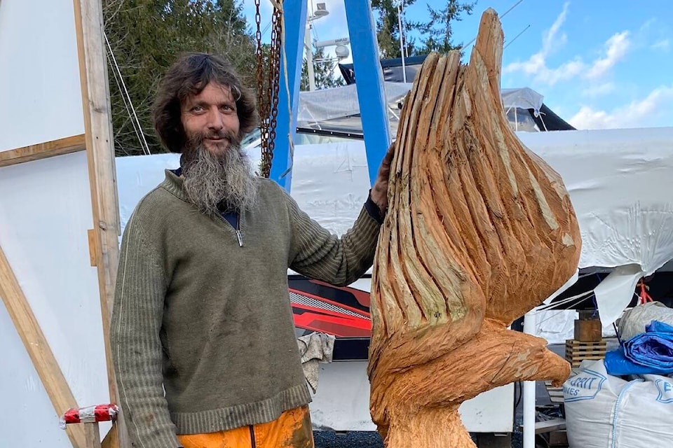 Cowichan Bay resident and carver Justin Spalek has made over 300 pieces of art since first using his chainsaw for creativity three years ago, Spalek stands next to the eagle he is carving out of red cedar at his place of employment in Maple Bay. (Chadd Cawson/Connector) 