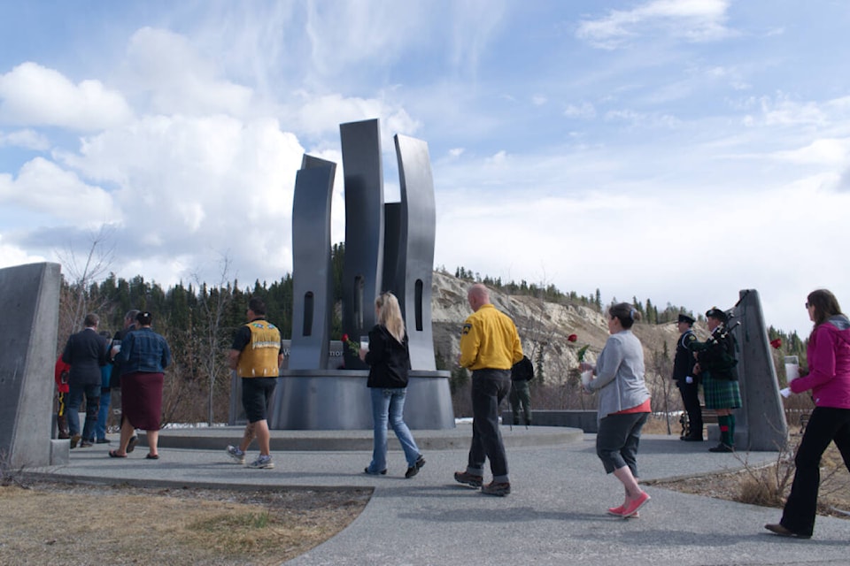 People place candles and flowers around the Yukon Workers’ Memorial to mark deaths and injuries that occur to workers on the job during the Day of Mourning held April 28. (Dana Hatherly/Yukon News) 