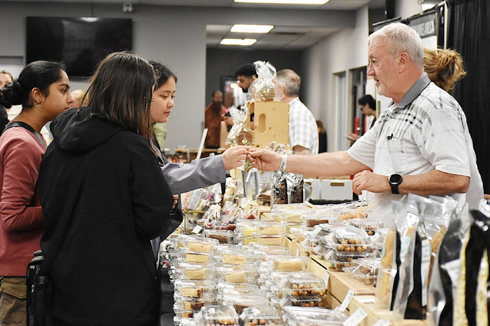 A woman takes a sample from Checkers Fudge in the sampling area at the Ridge Meadows Home Show. (Colleen Flanagan/The News) 