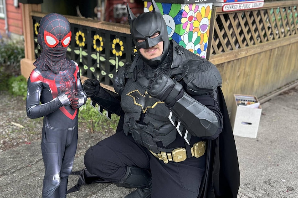 Cyprus Fischer and Batman catch up at the little free library in Fernwood during the May launch of the Little Free Library Superhero Adventure. (Photo by Constance Fischer) 
