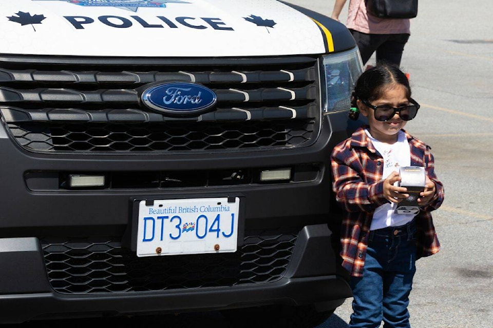 Jind Kaur, 2, poses for a photo in front of a police cruiser at the Surrey RCMP open house in Surrey Saturday, May 11, 2024. (Photo: Anna Burns) 