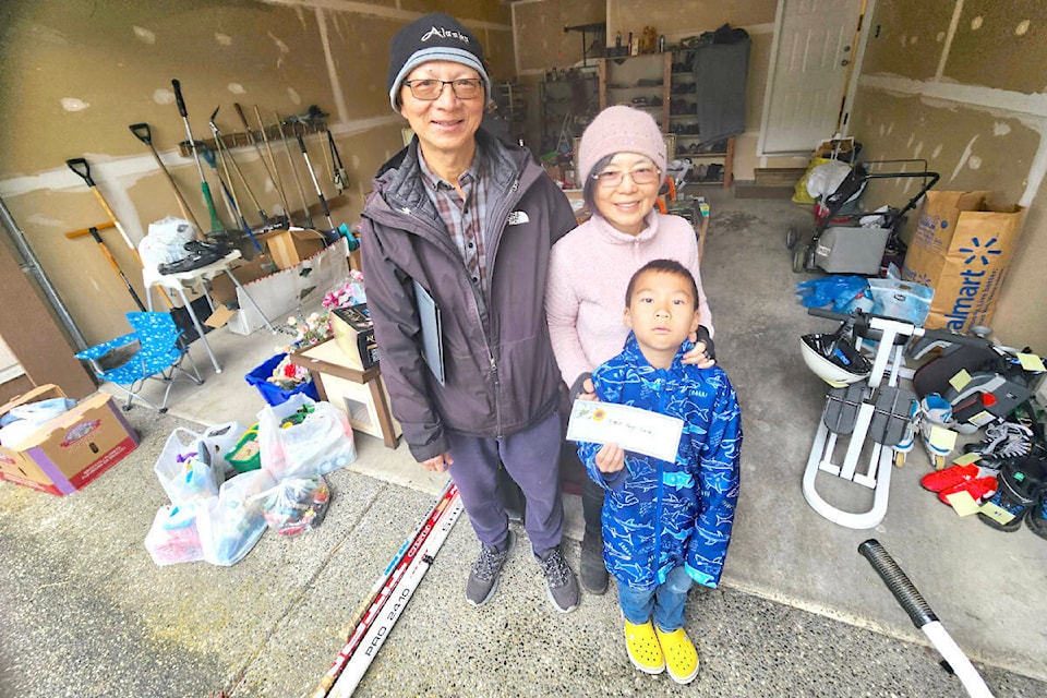 Willoughby residents Leo and Susan Chou, with grandson Connor, who was holding a toys for sale sign, were among 296 91ԭ addresses who signed up for the annual Township-wide Garage Sale, held over a wet and cold Saturday, May 25. (Dan Ferguson/91ԭ Advance Times) 