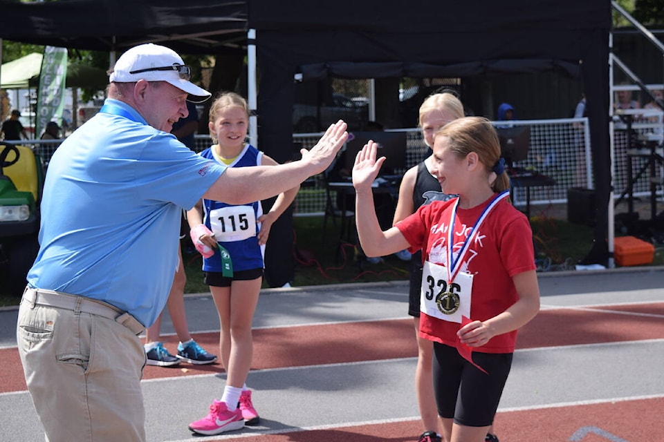Event organizer and volunteer Jim Bradshaw high-fives Everly Pidskalny after she won the 100 metre dash for her age group on June 5, 2024. (Brittany Webster/Capital News) 