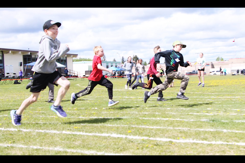 Kolton Hicks (left) grins as he races against Dylan Gruening, Polaris Adams and Malakai Gobin at 100 Mile Elementary School last week. (Patrick Davies photo - 100 Mile Free Press) 