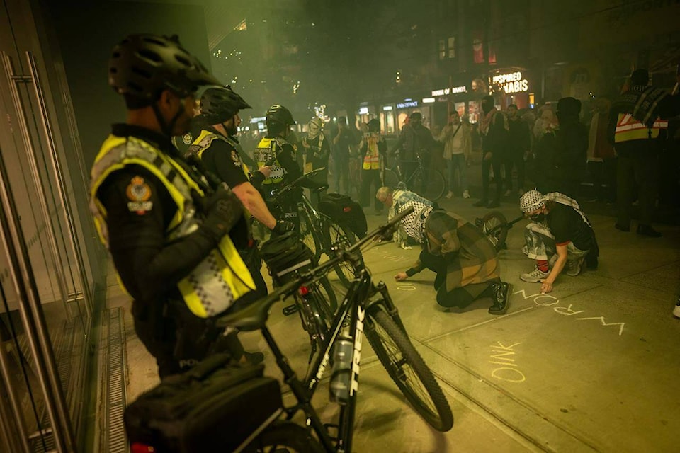 People write in chalk outside of a building during a pro-Palestine rally marking the anniversary of a Hamas attack on Israel in Vancouver, B.C., Monday, Oct. 7, 2024. (Ethan Cairns/Canadian Press)