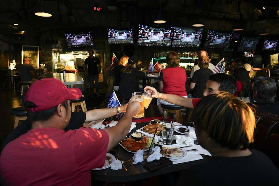 Supporters of former President Donald Trump drink beers as they watch him speak on television on July 18, 2024. As Americans head to the polls for a presidential election Tuesday, their compatriots and Canadian neighbours north of the border will be watching the results. (AP Photo/Ashley Landis) 