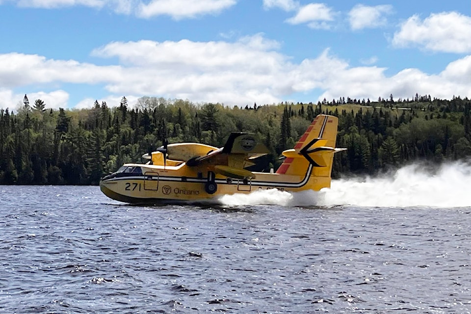 An Ontario CL-415 Super Scooper picks up water on a lake to drop on a wildfire.