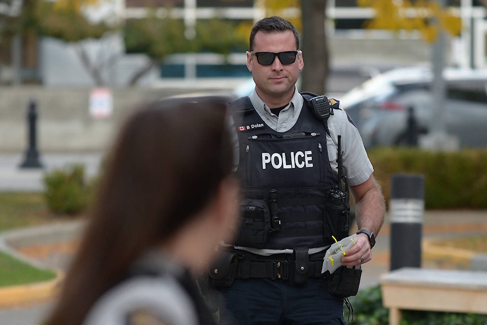 Officer holding the suspicious package left on a bench outside the Kelowna Law Courts on Oct. 7. (Phil McLachlan - Capital News)