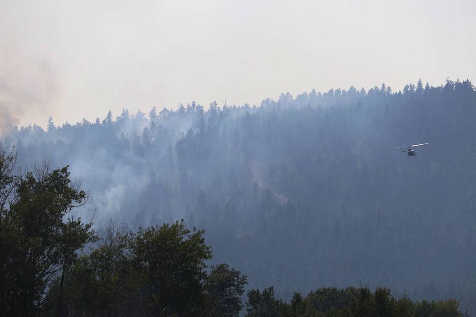 A helicopter surveys the Mount Law wildfire, just above Preston Road and Glonrosa Road in West Kelowna on Aug. 18. (Aaron Hemens/Capital News)