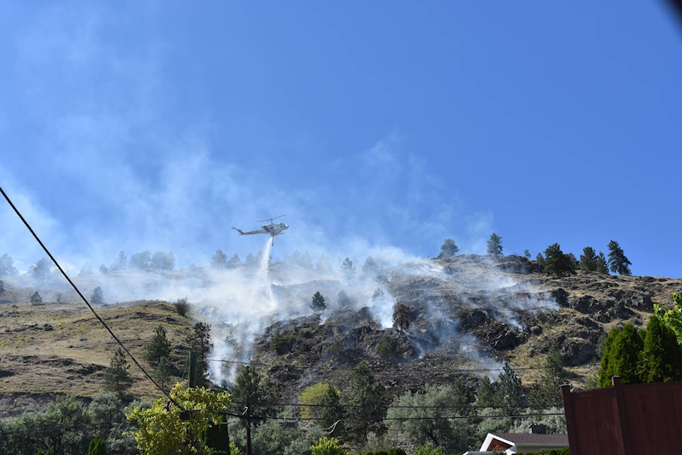 The grass fire near the Pine Hills golf course is being put out by bucket helicopters on Monday. (Facebook)