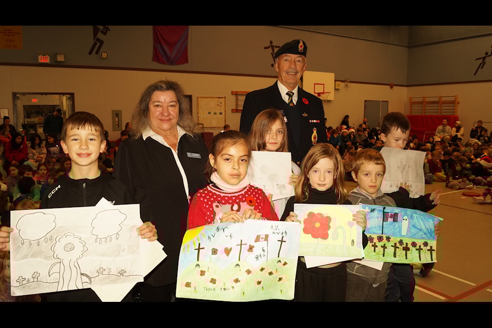 Contest winners from Ecole Poirier hold up their winning entries in this year's Sooke Legion Youth Remembrance Contest, with contest co-ordinator Ken levert, and Laurier Hicks, chair of this year's poppy campaign. (Rick Stiebel/News Staff)                      
