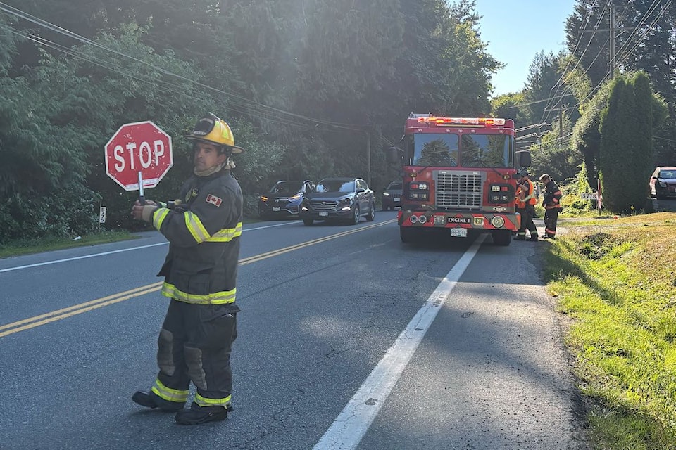 A firefighter directs traffic on the 5700 block of Sooke Road, as emergency crews respond to a incident involving two vehicles.