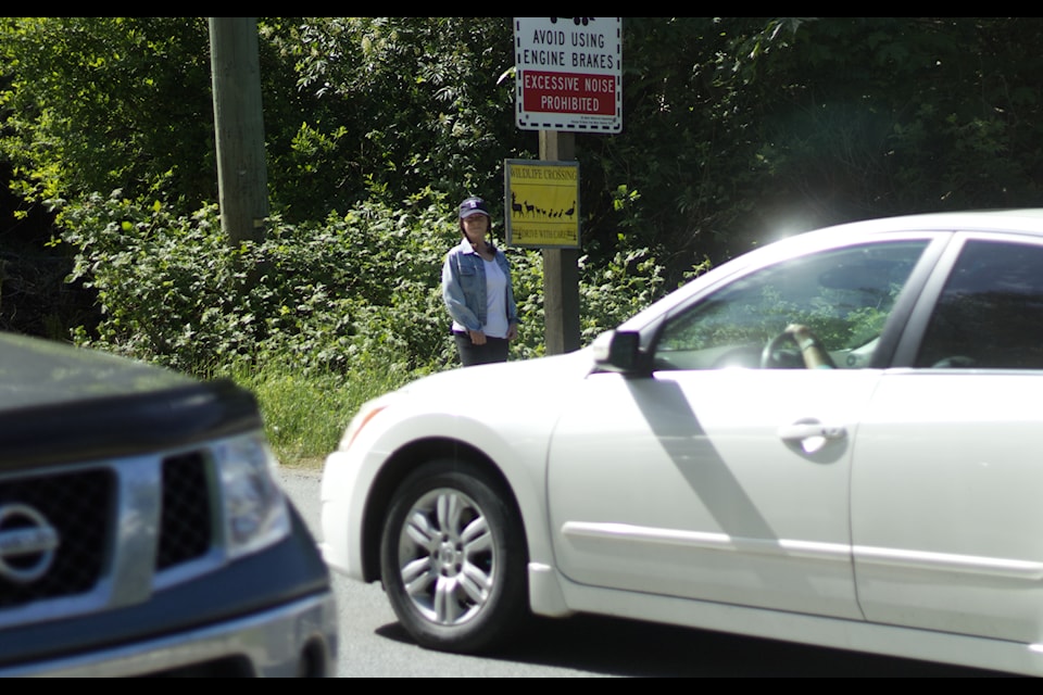 Kelly Chartier stands by one of her signs on a busy Sooke Road.