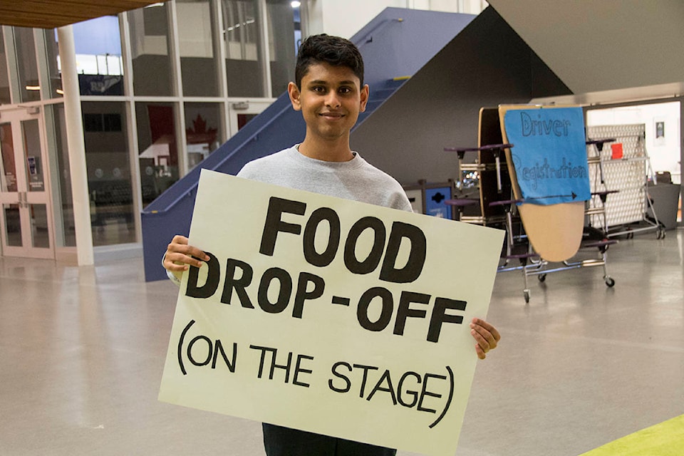 Royal Bay Secondary grade 12 student Adi Easwaran directs students with food donations to the stage during the 10,000 Tonight food drive Wednesday evening. (Nina Grossman/News Staff)