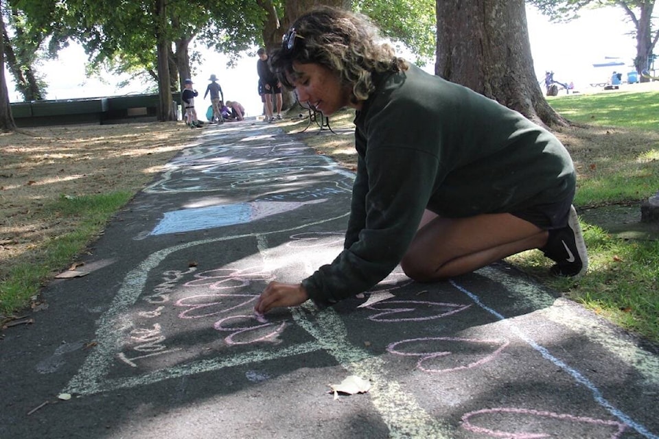 Lucy Aitken, a leader with Recreation Oak Bay helps campers use up the chalk to fill a colourful and inspiring trail at Willows Beach Park Sept. 2. (Christine van Reeuwyk/News Staff)