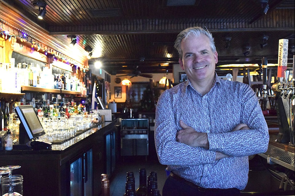 Morgan Watson, owner of Bartholomew’s Public House, behind a bar decked out with Christmas lights. (Kiernan Green/News Staff)