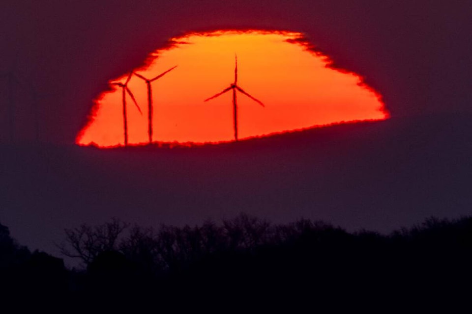 FILE - Wind turbines stand in front of the rising sun in Frankfurt, Germany, Friday, March 11, 2022. A United Nation-backed panel plans to release a highly anticipated scientific report on Monday, April 4, 2022, on international efforts to curb climate change before global temperatures reach dangerous levels. (AP Photo/Michael Probst, File)