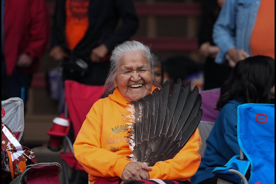 Kamloops Indian Residential School survivor Camille Kenoras holds eagle feathers as she laughs during a ceremony to mark the one-year anniversary of the TkÕemlœps te SecwŽpemc announcement of the detection of the remains of 215 children at an unmarked burial site at the former residential school, in Kamloops, B.C., on Monday, May 23, 2022. THE CANADIAN PRESS/Darryl Dyck