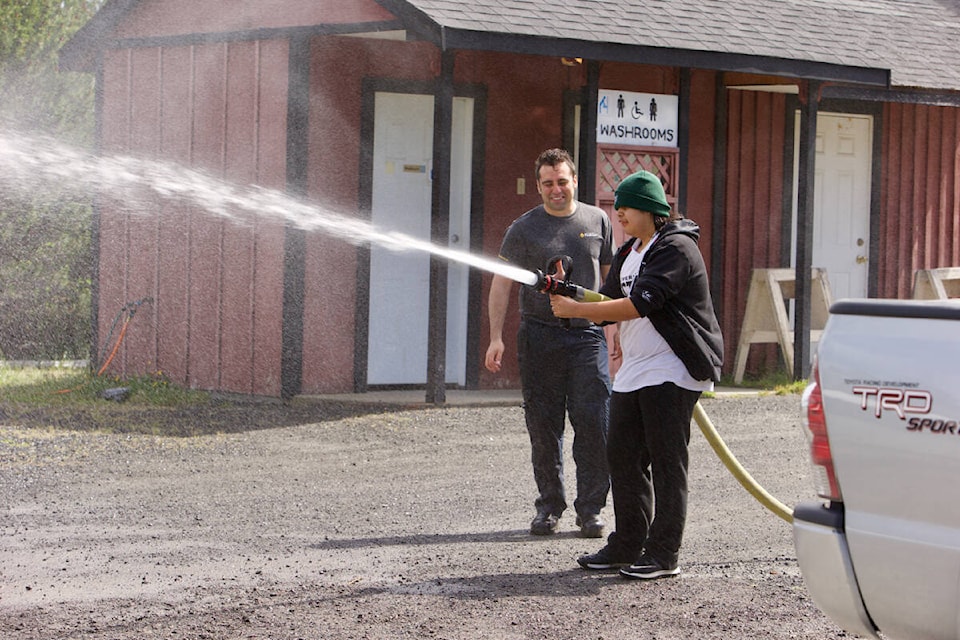 A West Shore resident tries out a fire hose during a Metchosin FireSmart community barbecue Saturday. (Justin Samanski-Langille/News Staff)