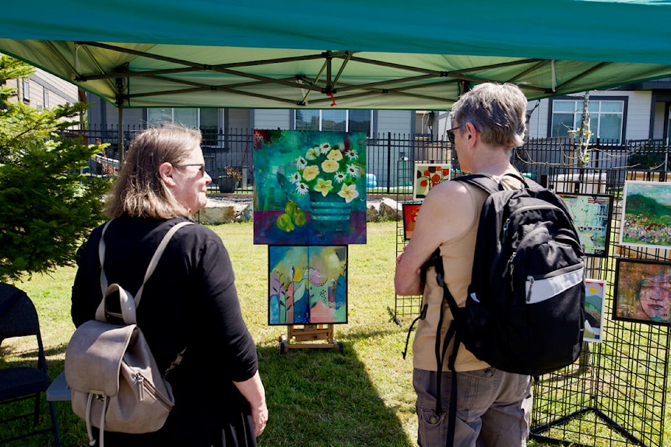 Visitors enjoy some of the artwork on display Saturday during Arts and Culture Colwood Society’s summer art show, held at Meadow Park. (Justin Samanski-Langille/News Staff)