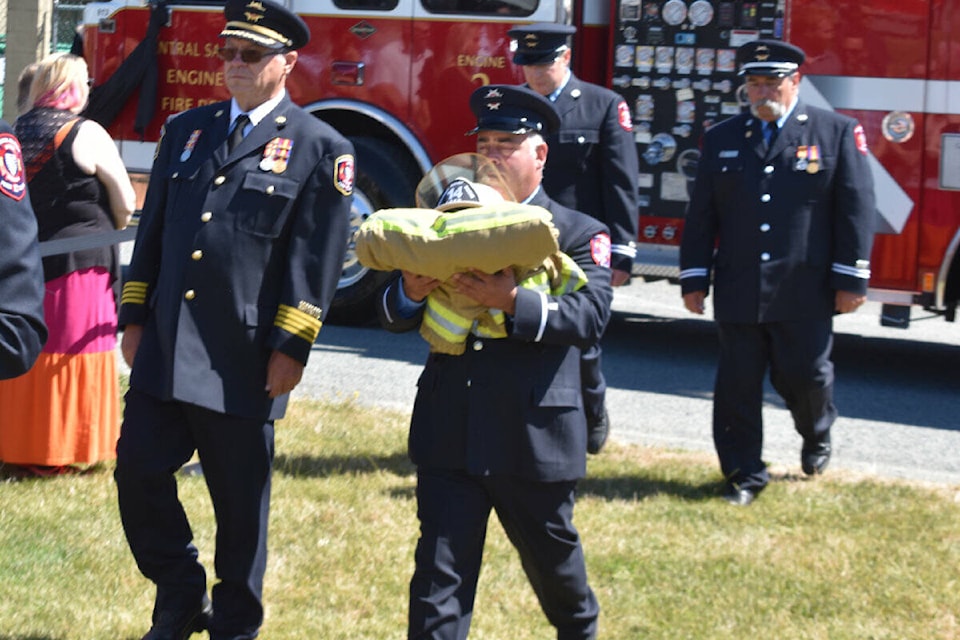 Firefighters carry the helmet and uniform of Forrest Owens into the RCMP Barn at the Saanich Fairgrounds. Some 800 people joined the memorial service Sunday. (Wolf Depner/News Staff)