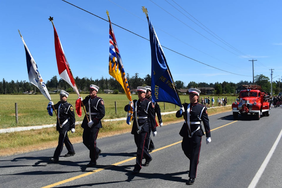 A colour guard led the procession of firefighters and other emergency crews representing various departments during Sunday’s memorial in honour of Forrest Owens, who had served as Central Saanich’s assistant chief during a career that spanned 35 years in firefighting. The procession, which featured some 200 people, started from Stelly’s Secondary School on the way to the Saanich Fairgrounds. (Wolf Depner/News Staff)