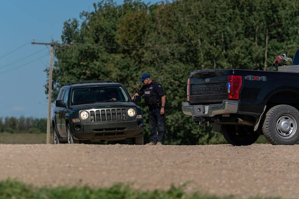 An RCMP officer interacts with a driver at a police roadblock in James Smith Cree Nation, Sask., on Tuesday, September 6, 2022. A manhunt for the fugitive suspect in the Saskatchewan mass killing continues today after a tense police search yesterday came up empty. THE CANADIAN PRESS/Heywood Yu