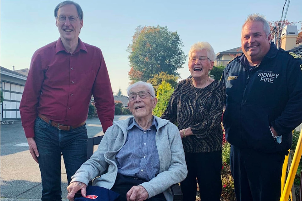 Former Sidney firefighter Ted Clarke celebrates his 100th birthday with a fire brigade parade and photo with Mayor Cliff McNeill-Smith (left) and Deputy Fire Chief Mike Harman (right). (Town of Sidney/Facebook)