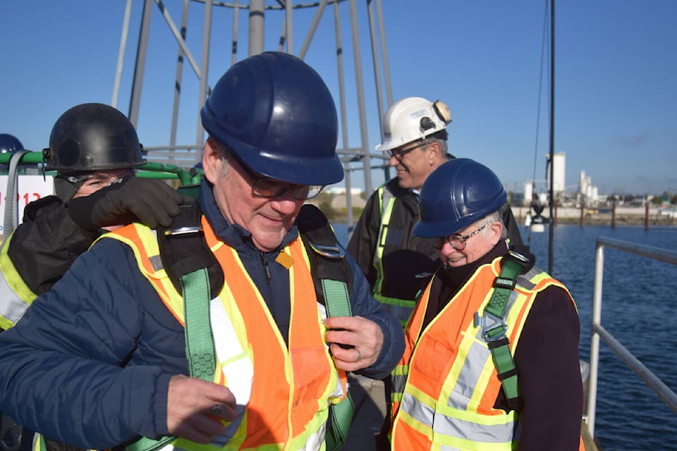 Victoria Mayor Marianne Alto and Bruce Williams secure themselves with harnesses before they are lifted to the top of the 42-foot tree. (Hollie Ferguson/News Staff)