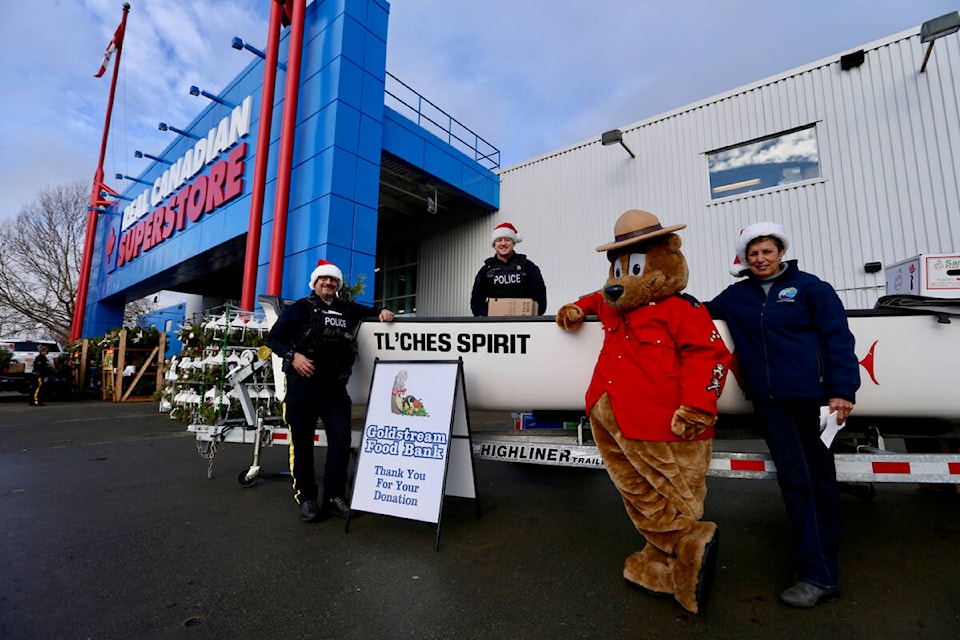 Members of the West Shore RCMP, including mascot Safety Bear, stand in front of the 35-foot canoe they filled with donated food Saturday (Dec. 10) during the detachment’s annual food drive. (Justin Samanski-Langille/News Staff)