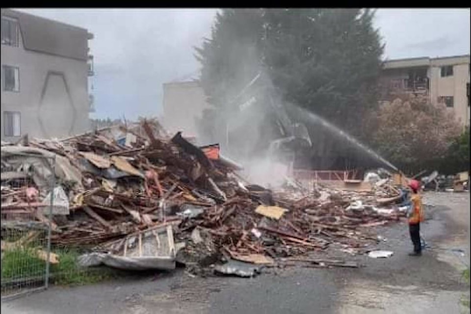 A man spraying water on the demolition site with dust rising in the background. (Courtesy of Maria Hendrikx)