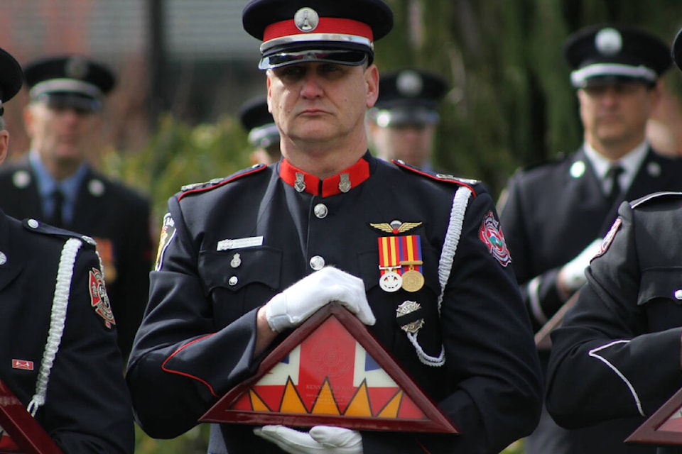 Oak Bay Fire Lt. Jason Joynson holds the flag of fallen colleague chaplain Kenneth Gill, who took his own life in 2018, at the south lawn of the legislature in Victoria Monday (March 6). (Austin Westphal/News Staff)