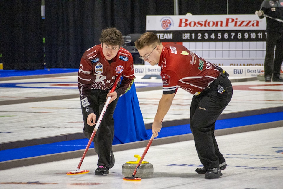Two members of team Kiist sweep during Draw 3 of the Boston Pizza Cup.