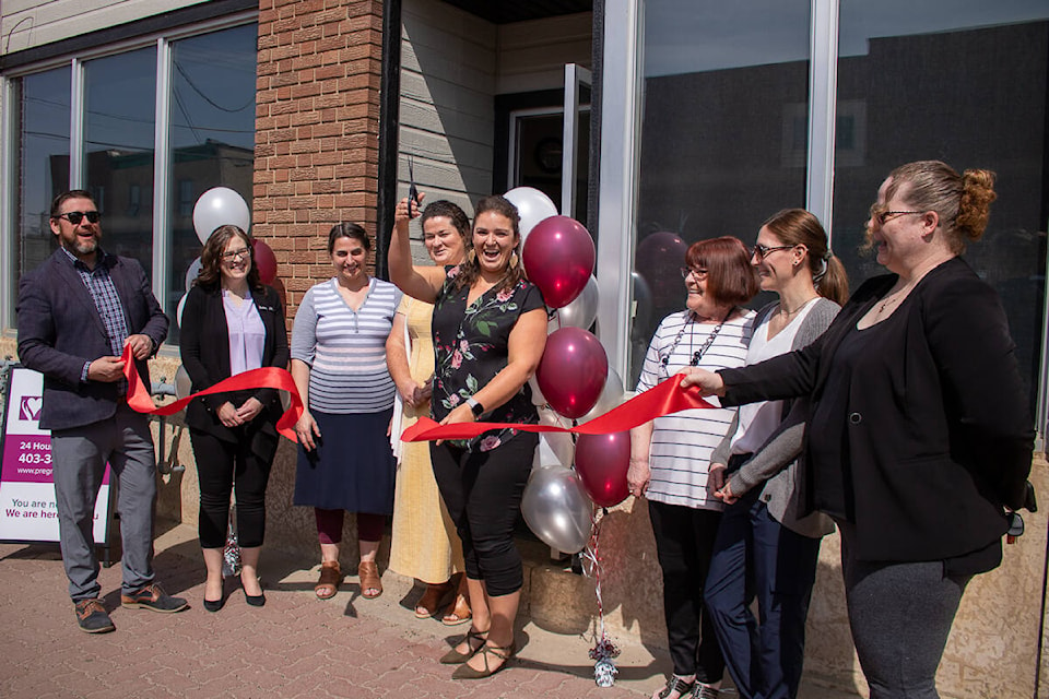 Interim director of the Stettler Central Alberta Pregnancy Care Centre Jenessa McAuley cuts the ribbon held across the doorway by Mayor Sean Nolls and Donna Morris from the Stettler Regional Board of Trade, celebrating the grand opening of the facility. (Kevin Sabo/Stettler Independent)