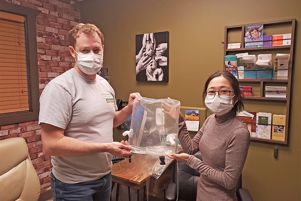 Williams Lake physician Dr. Ivan Scrooby and medical graduate student Vionarica Gusti hold up the COSMIC Bubble Helmet. Both are part of the non-profit organization COSMIC Medical which has come together to develop devices for treating patients with COVID-19. (Monica Lamb-Yorski photo - Williams Lake Tribune)