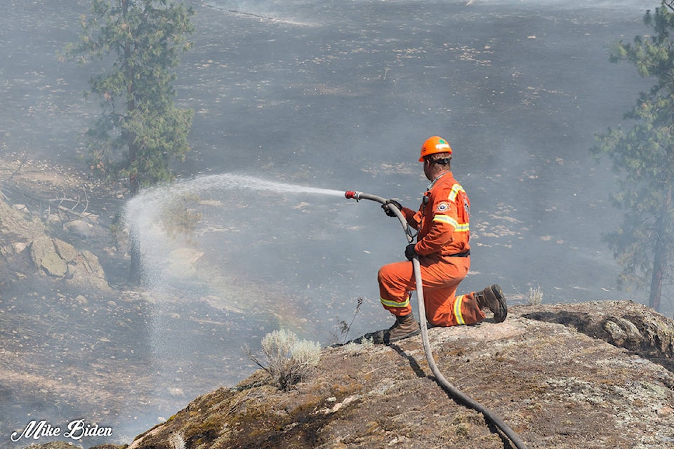 A firefighter works to put out hot spots at the Thomson Creek fire Sunday. (Mike Biden photo)