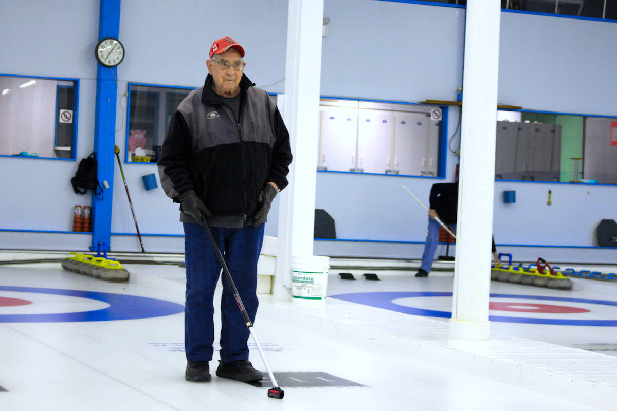 Clarence Boettger watching on as his rock skids down the ice. (Josh Piercey/Revelstoke Review)