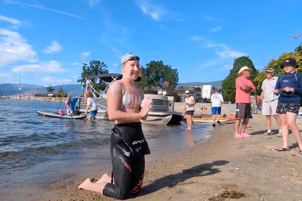 Issie Grecoff, 16, goes to her knees on the shores of Okanagan Lake in Penticton on Aug. 14 after swimming 12 hours from Peachland to Penticton. The Penticton teen has raised over $10,000 so far for Alzheimer’s research. (YouTube)