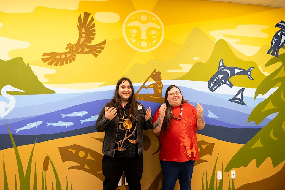 Mural artists Nova Wolf, left, and Chase Gray pose for a photo in front of the Indigenous mural they painted at DIVERSEcity in Surrey on Friday, Jan. 24, 2025. 