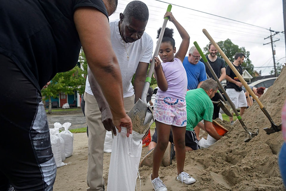 Nyla Trepagnier, center, fills a sandbag held by her grandparents Heloise and Ronald Nelson, left, at a sandbag station provided by local bar the Mid-City Yacht Club in New Orleans, La. Friday, July 12, 2019. The city did not provide sandbag stations on the lead up to Tropical Storm Barry this weekend. The system in the Gulf of Mexico is expected to make landfall, possibly as a hurricane, near Morgan City on Saturday morning. (Max Becherer/The Advocate via AP)