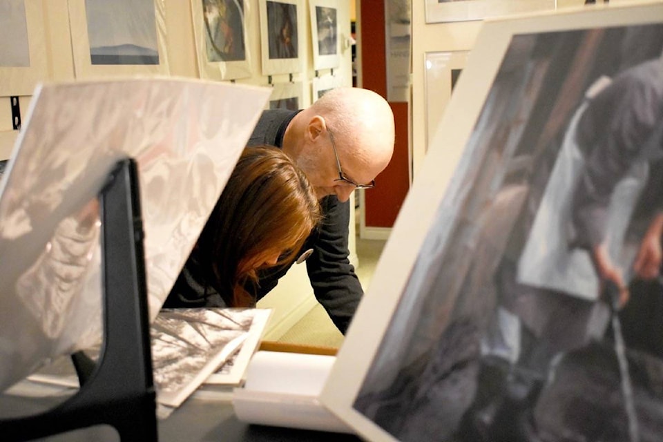 Photographer Wayne Turner shows a visitor a selection of prints during the 2019 Delta Studio Stomp. Many of them were the same photographs printed on different kinds of paper to demonstrate the remarkable impact the medium alone can make on the look of a print. (James Smith photo)