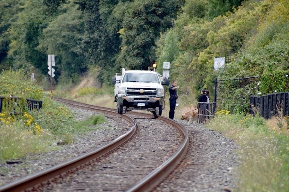 BNSF Special Agent Darrell Ell chats with two pedestrians who dodged no-trespassing signage with their dog Thursday (Aug. 20) in an effort to access White Rock’s west beach, ending up on restricted land. Ell explained the rules and the safety reasoning behind them, and let the pair off with a warning. (Tracy Holmes photo)