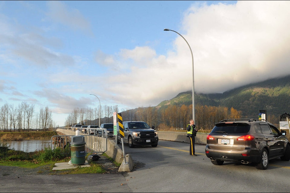 An RCMP officer tells a driver they need to turn around and head towards Chilliwack while guiding traffic on the east side of the Keith Wilson Bridge. Folks from Sumas Prairie and Yarrow were leaving the area following an evacuation order on the morning of Tuesday, Nov. 16, 2021. (Jenna Hauck/ Chilliwack Progress)