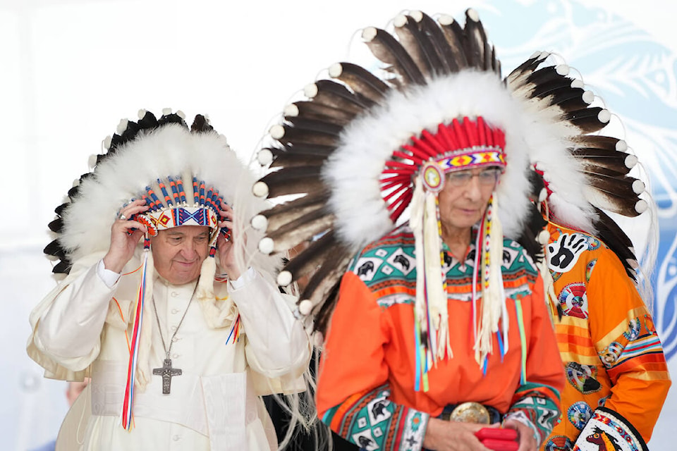 Pope Francis adjusts a traditional headdress he was given after his apology to Indigenous people during a ceremony in Maskwacis, Alta., as part of his papal visit across Canada on Monday, July 25, 2022. THE CANADIAN PRESS/Nathan Denette