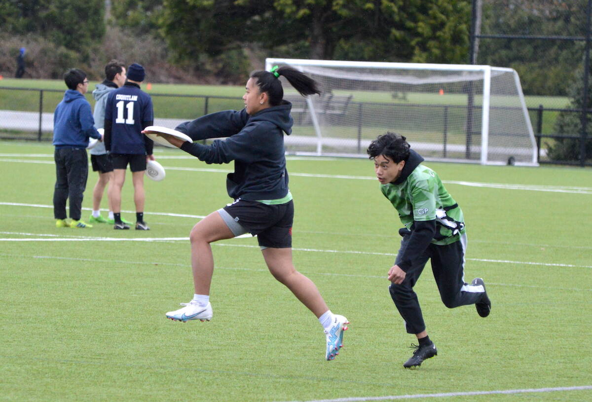 Kiara Valdez grabs a disc followed by Caleb Munoz during warmup for Guildford Park Secondarys senior ultimate team at Newton Athletic Park on Thursday, April 20, 2023. (Photo: Tom Zillich)
