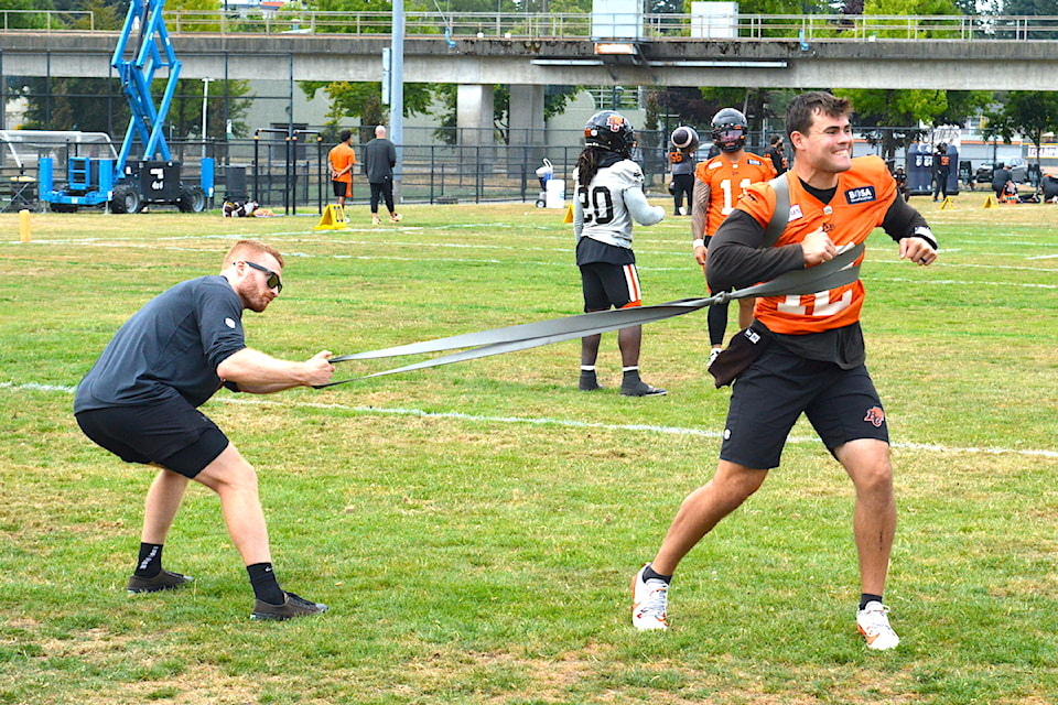 BC Lions quarterback Nathan Rourke exercises with the help of a staff member during practice at the CFL team's facility in Surrey on Tuesday, Aug. 5, 2025. 